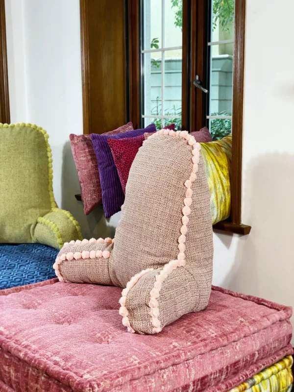 Close-up of a pastel pink textured backrest cushion with pom-pom accents on a Mah Jong daybed.