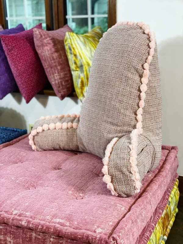 Close-up of French daybed Mah Jong sofa showcasing plush backrest cushions with pom-pom trim on patterned bases.