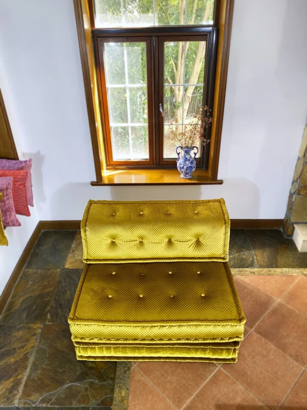 Top-down view of a French Mah Jong daybed in golden-yellow upholstery, with natural light streaming through a nearby window.