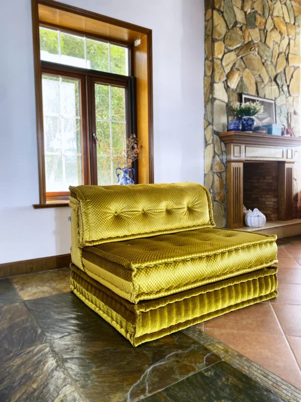 French Mah Jong daybed in golden-yellow fabric, styled with a blue vase and natural lighting from large windows.