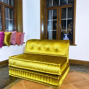 French Mah Jong daybed with luxurious golden-yellow upholstery, placed in a cozy corner with decorative pillows.