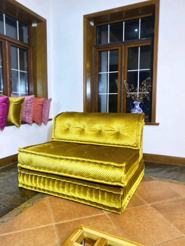 French Mah Jong daybed with luxurious golden-yellow upholstery, placed in a cozy corner with decorative pillows.