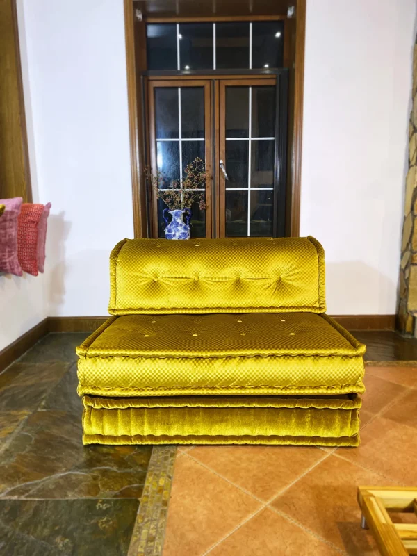 Vibrant golden-yellow French Mah Jong daybed in a living room with a patterned floor and natural lighting.