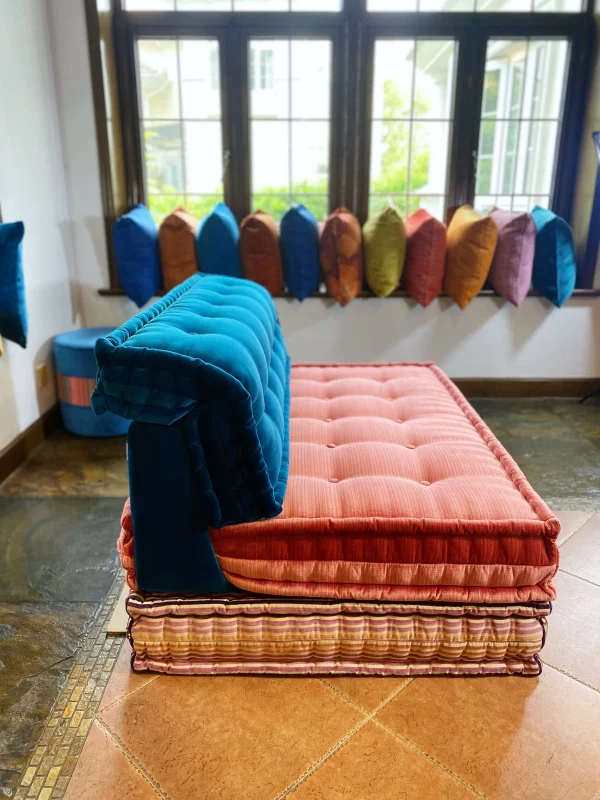 Mah Jong modular sofa in blue and pink with vibrant cushions in a well-lit living room.