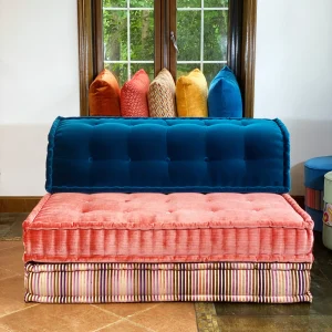 Mah Jong modular sofa in blue and pink fabrics with colorful pillows in a sunlit room.