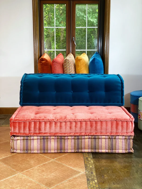 Mah Jong modular sofa in blue and pink fabrics with colorful pillows in a sunlit room.