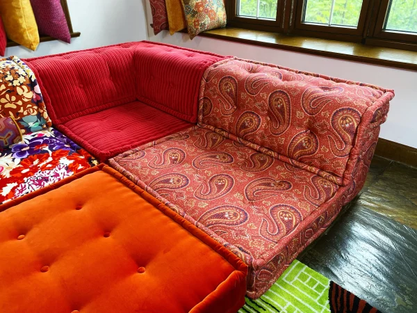 Modular Mah Jong sofa with a bold red paisley pattern, paired with corduroy and floral modules.