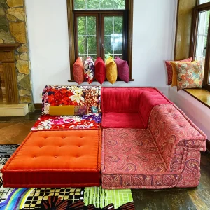 Corner section of a French Mah Jong sofa in red corduroy and paisley prints