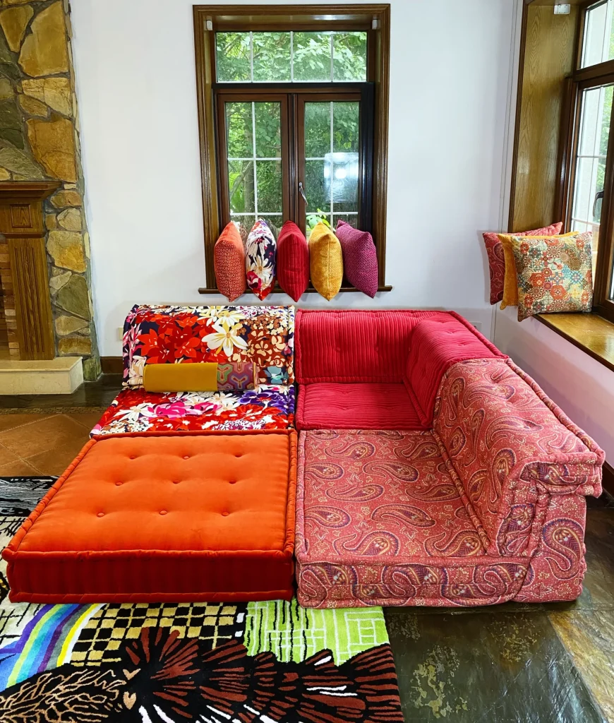 Corner section of a French Mah Jong sofa in red corduroy and paisley prints