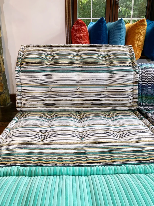 Wide-angle view of a vibrant Mah Jong sofa styled with playful patterns, ribbed textures, and colorful cushions in a sunlit room.