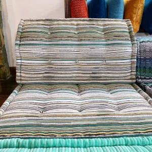 Wide-angle view of a vibrant Mah Jong sofa styled with playful patterns, ribbed textures, and colorful cushions in a sunlit room.