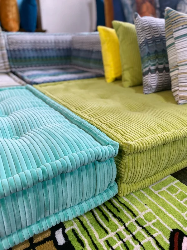 Striped Mah Jong sofa with ribbed green and teal textures, styled with a leopard print bolster and bold cushions.