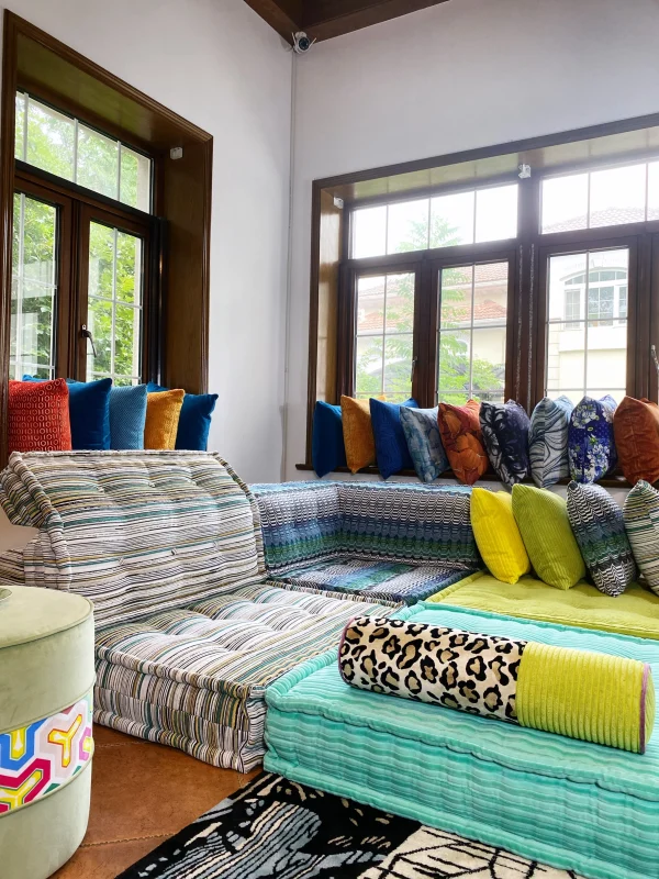 L-shaped Mah Jong sofa in striped and solid-colored patterns, styled with a leopard print bolster and colorful cushions.