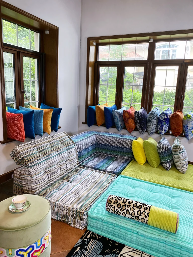 Stylish Mah Jong sofa in teal, green, and striped patterns, paired with yellow and multicolored cushions in a contemporary living room.