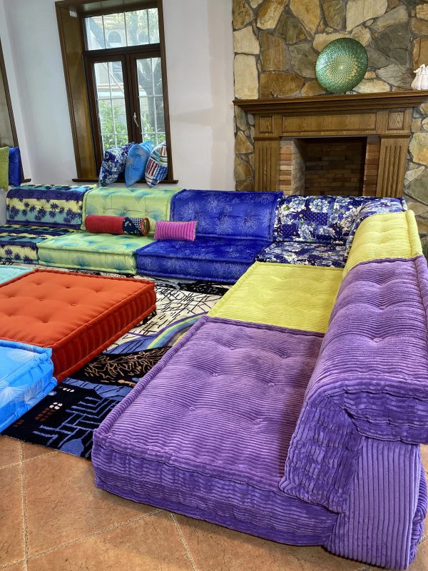 Layered cushions of the Mah Jong sofa with complementary colors in an open-plan space.