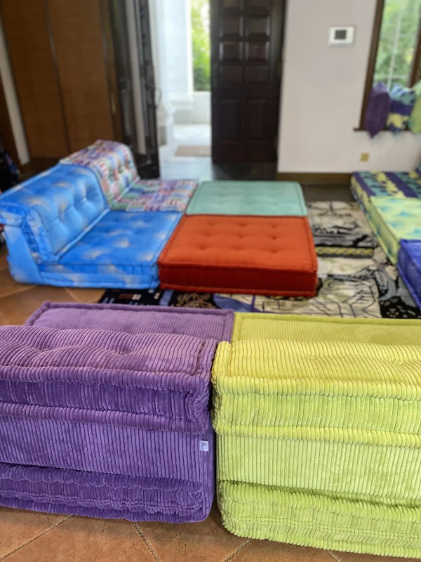 Full view of the Mah Jong sofa in a living room with colorful cushions and open doors leading to a garden.