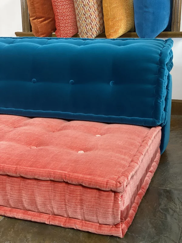 Close-up top view of the tufted cushions on a Mah Jong-style sofa in deep blue and coral pink.