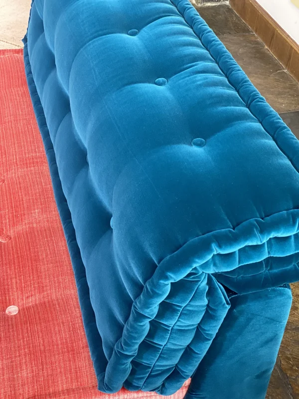 Detail of deep blue and coral pink velvet cushions on a Mah Jong-style sofa, showcasing its modular design.