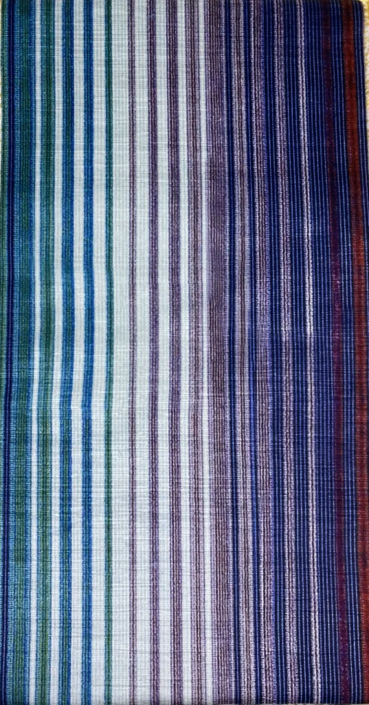 Close-up view of a multi-colored striped fabric with green, purple, and blue hues, showcasing a gradient pattern.