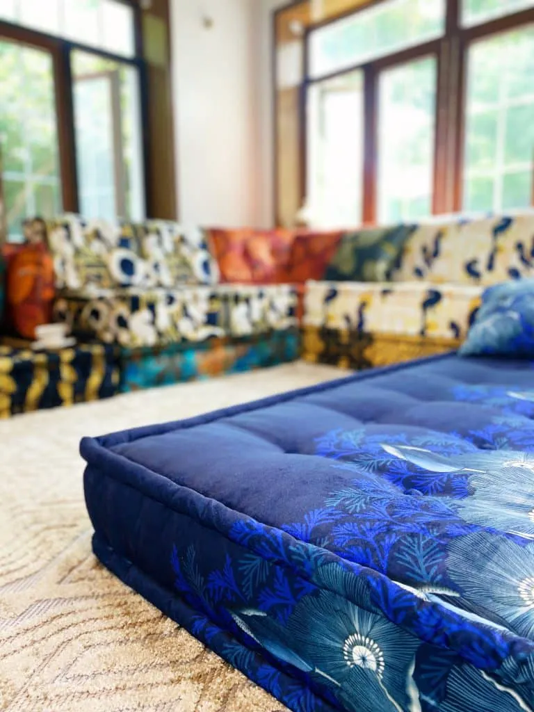 Tufted daybed in navy velvet with a blue floral print, in front of the modular sofa