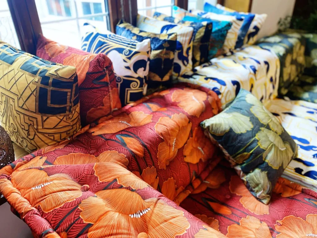 Complementary pillows made from leftover fabric, resting on a sofa in orange poppy and art deco prints