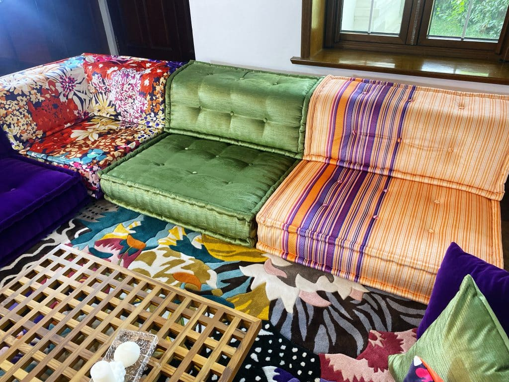 Modular sofa with an orange and purple striped section next to green velvet and floral modules