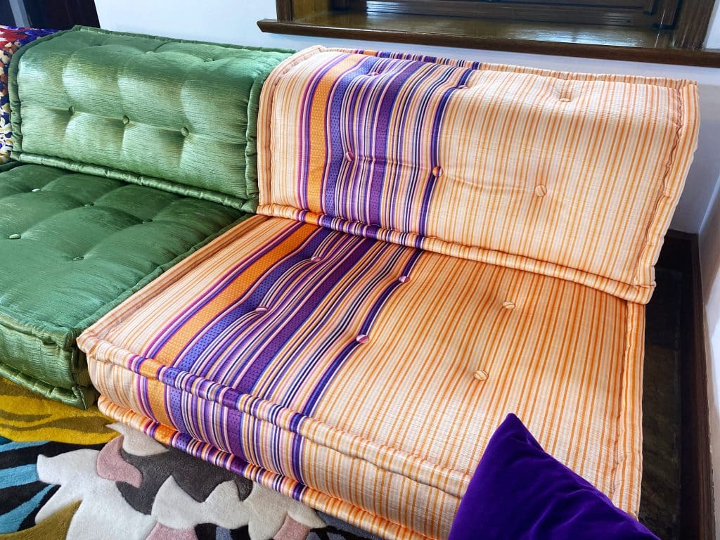 Flat stripe pattern of fine orange lines with a wide band of purple, orange, and pink stripes left of center