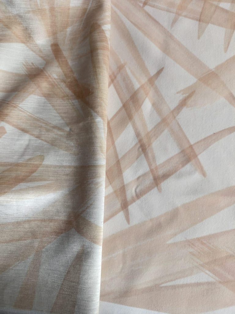 Two palm print fabric samples with soft tan brushstrokes on cream, showing how the design looks on different textures