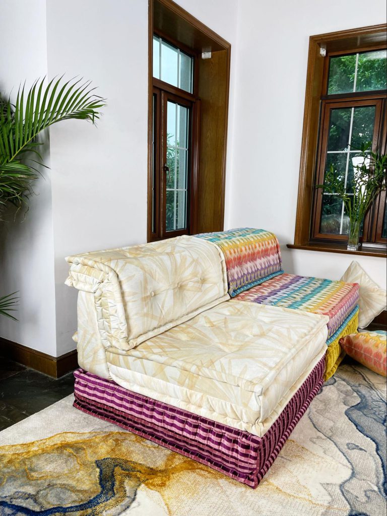 Mah Jong single seater in a golden palm print, beside a rainbow zigzag module on a marble-pattern rug