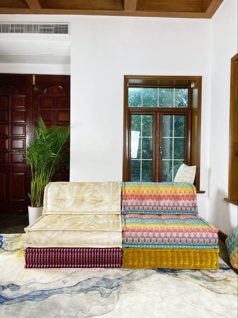 Palm print Mah Jong module next to a rainbow zigzag module, with a matching palm pillow in the window