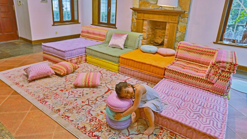 Child lounging on a colorful sofa styled with round and square pillows.