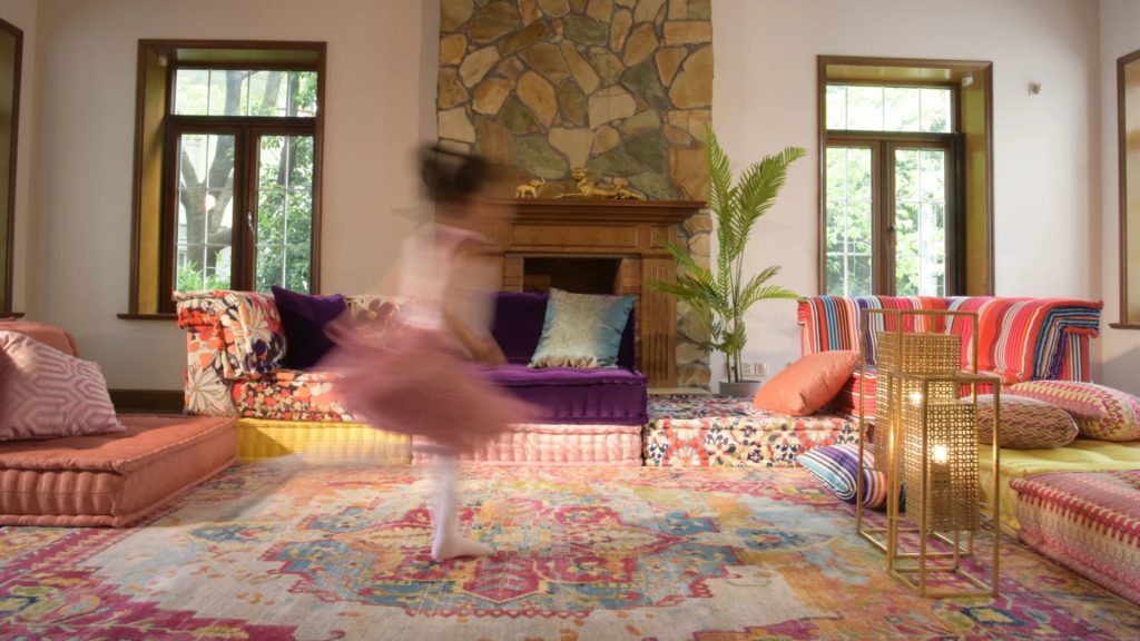Adorn Croft's bespoke rug in a cozy living room with colorful sofas and a child running.