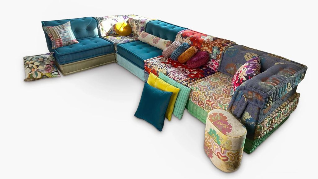 Adorn Croft's Monica colorful sofa decorated with vibrant upholstery and decorated with pillows and an ottoman.