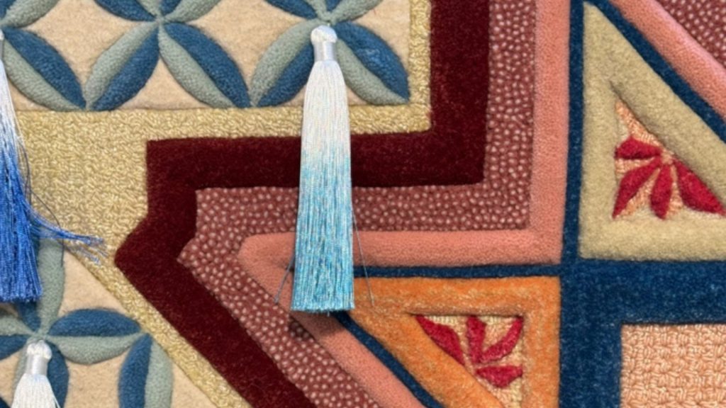 Closeup of a custom rug with abstract shapes, various textures, and a tassle.