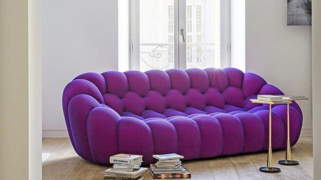 Adorn Croft's three-seater Bubble sofa in purple upholstery with a side table in a living room.