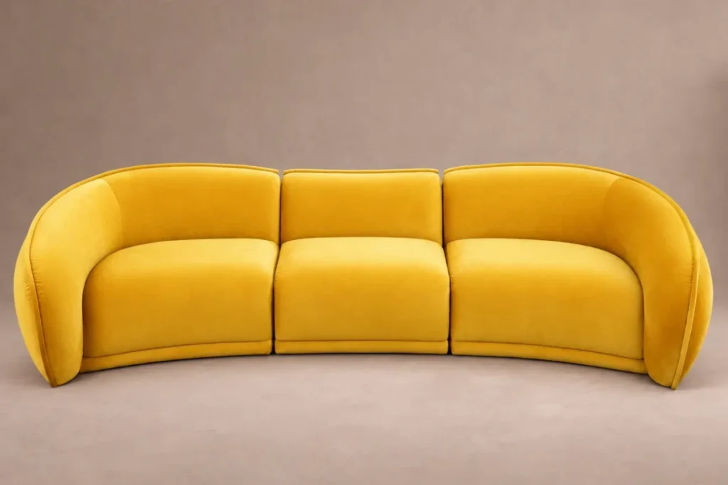 Adorn Croft's Elva curved sofa in yellow velvet on a plain studio background