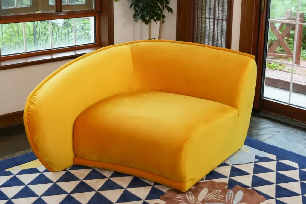 One end section of the Elva curved sofa in yellow velvet, showing its wraparound arm