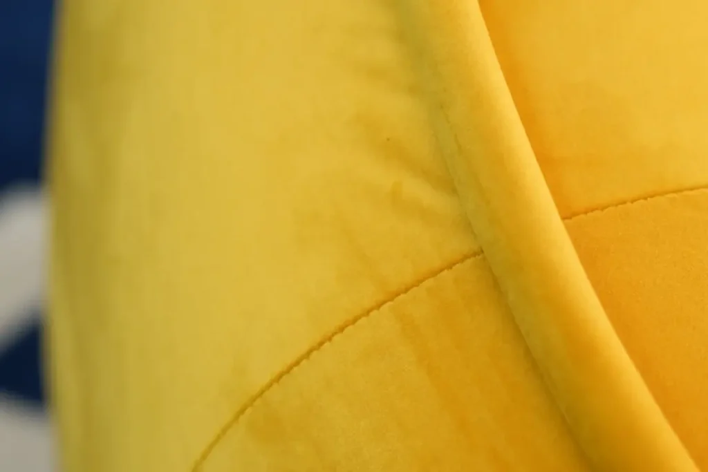 Close-up of the piped edge along the Elva sofa's yellow velvet arm