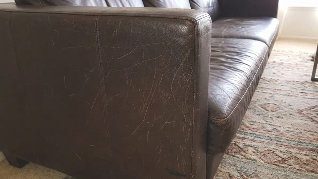 A dark brown leather sofa with cat scratches.