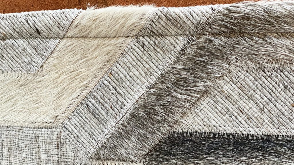 A closeup image of a cowhide rug with multiple patterns.