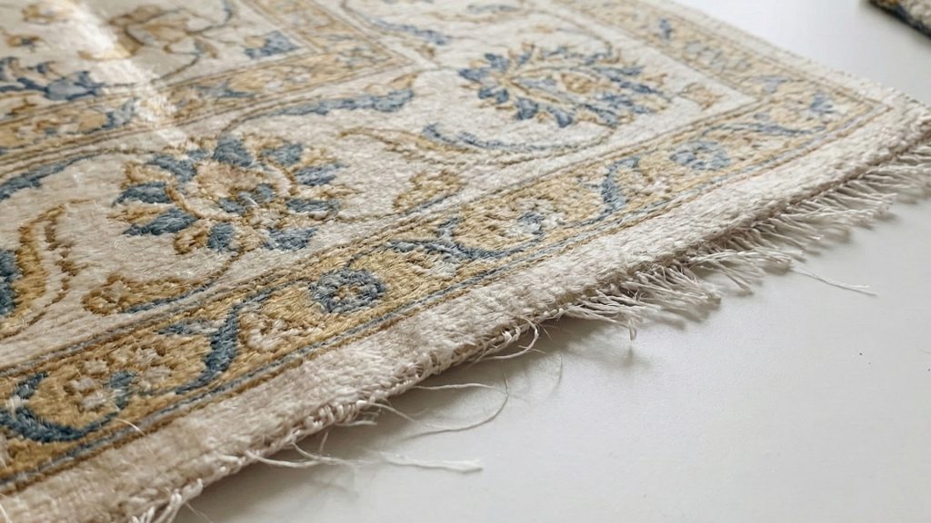 A close-up image of a delicate silk rug surface showing an elegant but fragile texture.