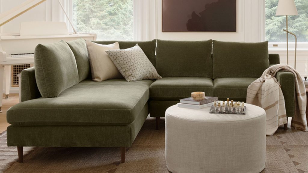 Interior Define's Sloan sofa in a green upholstery with two throw pillows.