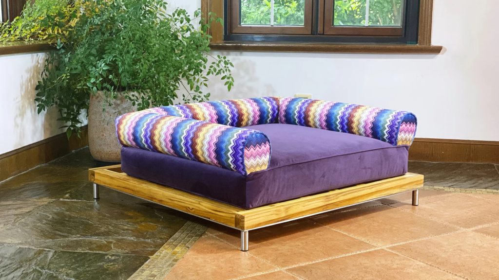 A purple pet bed with a teak wood base.