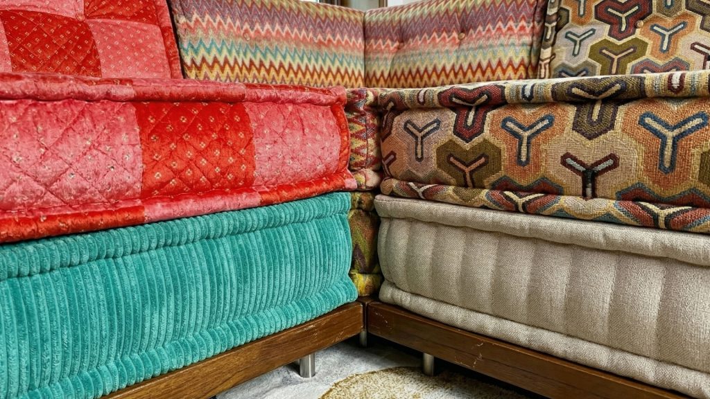 Closeup of the colorful sofa, highlighting its teakwood base and two-layered mats with vibrant upholstery.
