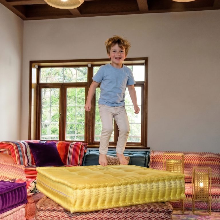 Kid jumping on a modular sofa cushion.