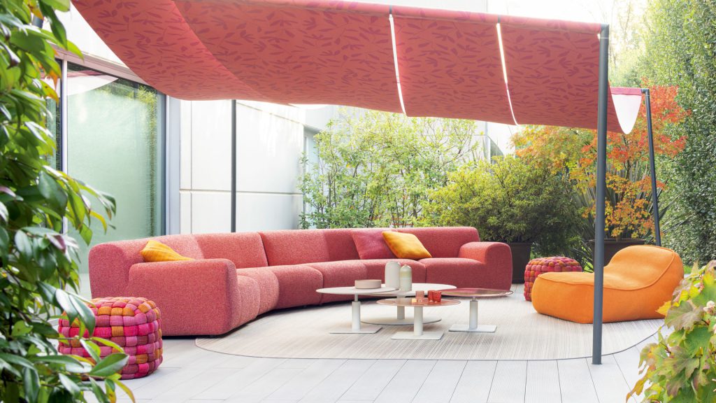 Paola Lenti's Welcome sofa upholstered in vibrant coral fabrics in an outdoor area.