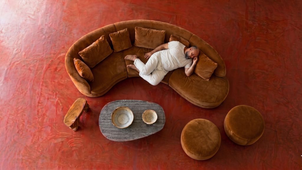 Overhead shot of a heavy man on a brown rounded sectional