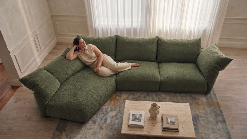 Lady lounging on Adorn Croft's Petal Sofa in olive fabric showing the full oversized sectional configuration