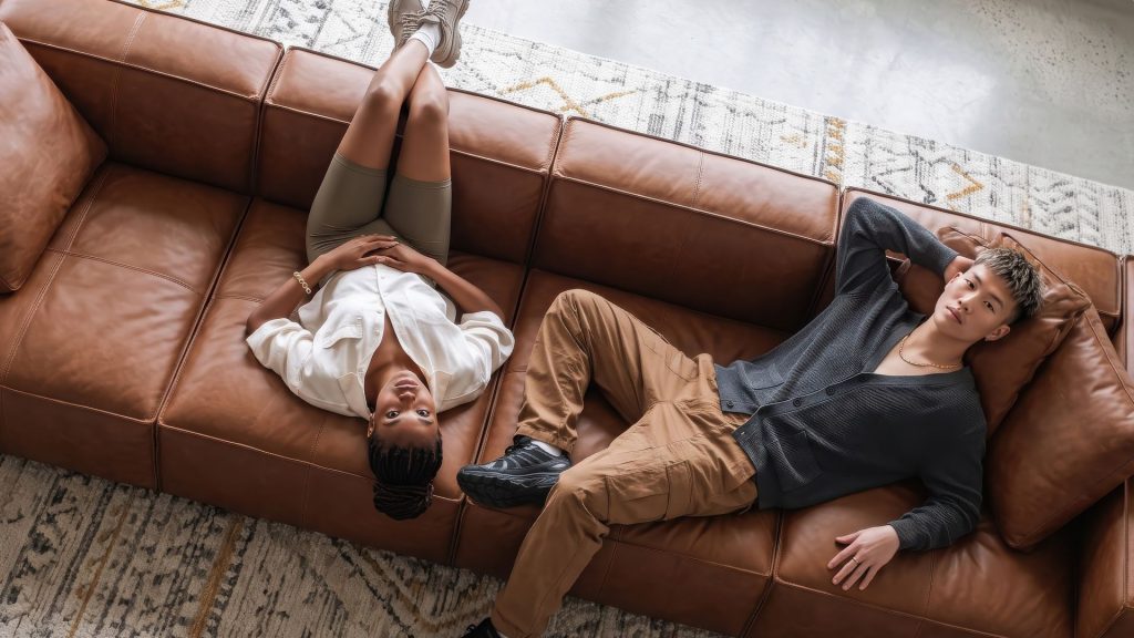 Girl and a boy lounging on a brown genuine leather sofa