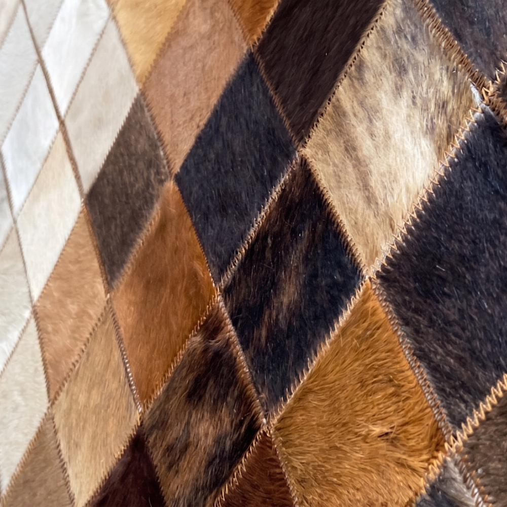 Cowhide patchwork rug in a diamond pattern with precision-stitched seams and different hide colors